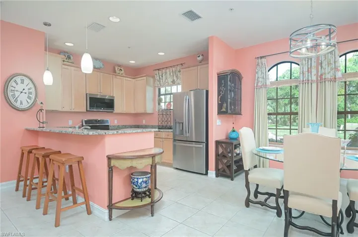 Kitchen with appliances with stainless steel finishes, light tile flooring, and pendant lighting