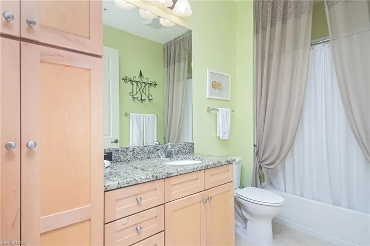 Full bathroom featuring tile floors, shower / tub combo, vanity, and toilet