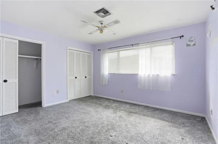 Unfurnished bedroom featuring two closets, carpet flooring, and ceiling fan