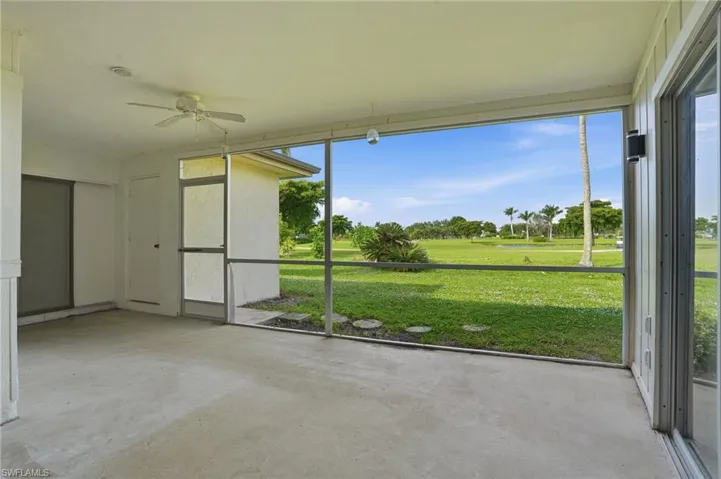 Unfurnished sunroom with ceiling fan and golf course view