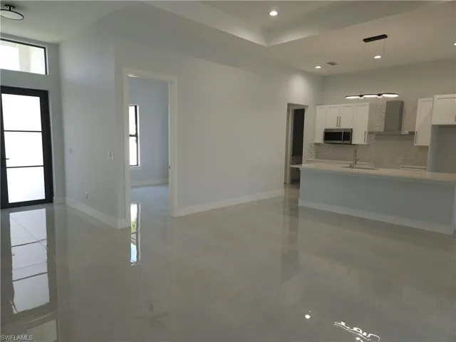 Unfurnished living room with a high ceiling, sink, a wealth of natural light, and light tile patterned floors