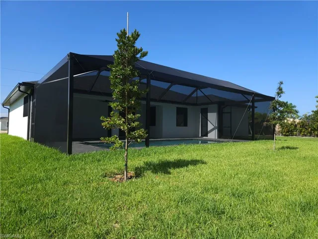 Rear view of house with a yard and glass enclosure
