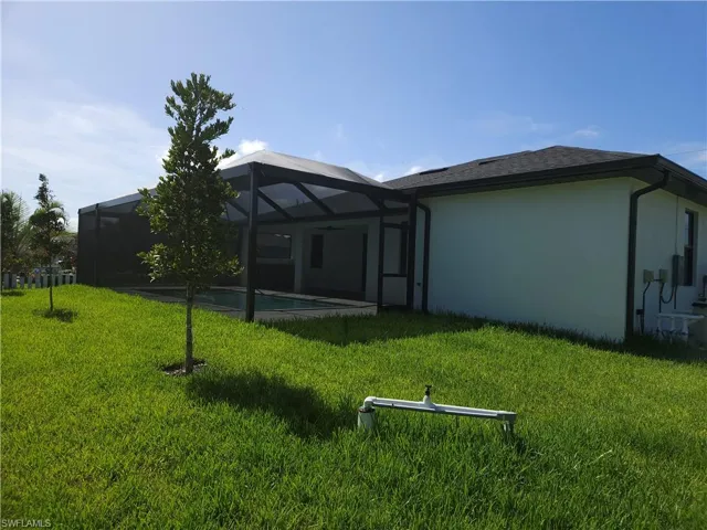 Back of property featuring a lanai and a lawn