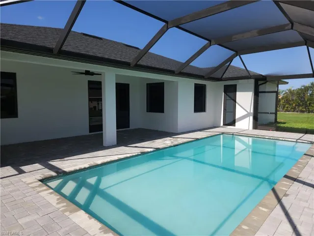 View of swimming pool featuring glass enclosure, a patio area, and ceiling fan