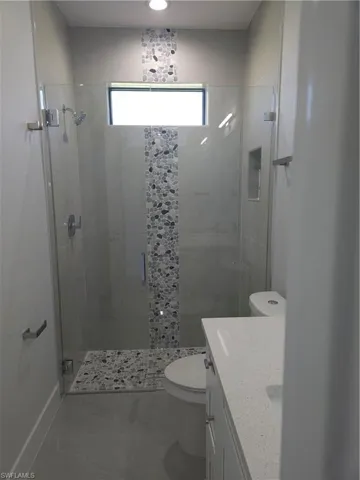 Bathroom featuring vanity, toilet, a shower with door, and tile patterned flooring