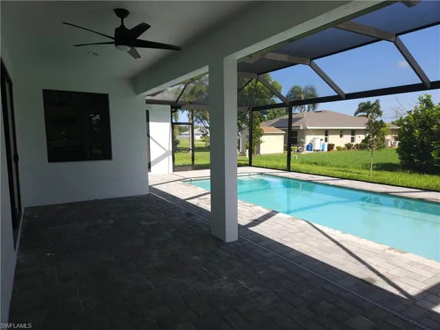 View of pool with a lanai, a patio area, a yard, and ceiling fan