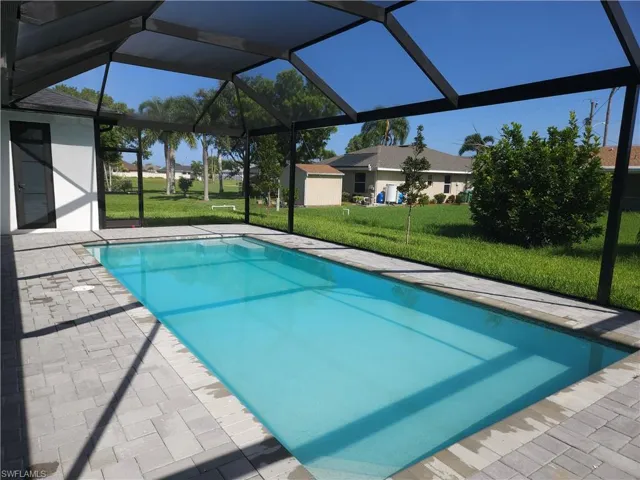 View of swimming pool with a patio, a yard, and glass enclosure