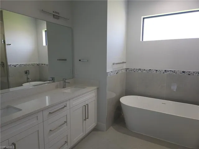 Bathroom with plenty of natural light, tile patterned flooring, and dual bowl vanity