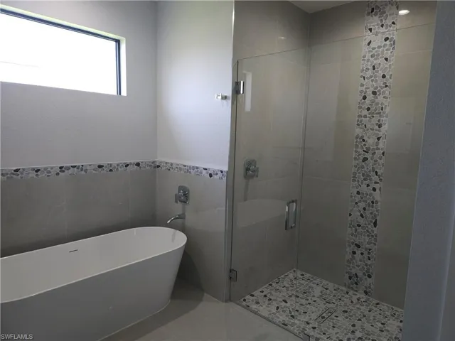 Bathroom featuring independent shower and bath, tile patterned flooring, and tile walls