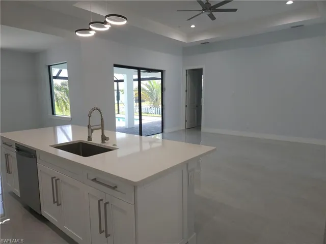 Kitchen featuring sink, pendant lighting, an island with sink, dishwasher, and a raised ceiling