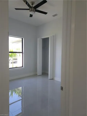 Unfurnished bedroom with light tile patterned flooring, ceiling fan, and a closet