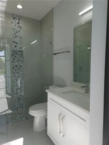 Bathroom featuring vanity, toilet, tile patterned flooring, and an enclosed shower