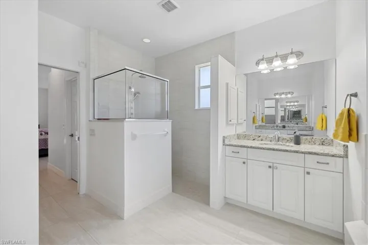 Full masted bathroom with ensuite bath, vanity, walk in shower, and light tile patterned floors