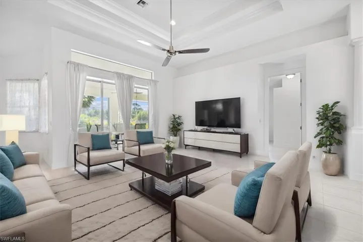 Living area featuring a raised ceiling, crown molding, and a ceiling fan virtualy staged