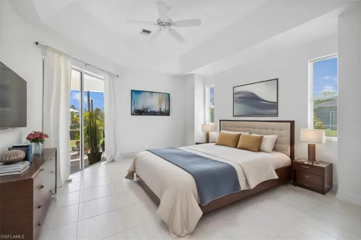 Master Bedroom featuring a tray ceiling, access to outside, light tile patterned floors, and ceiling fan virtually Staged