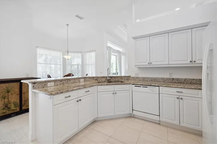 Kitchen featuring white cabinetry, light stone countertops, white appliances, a peninsula, and decorative light fixtures