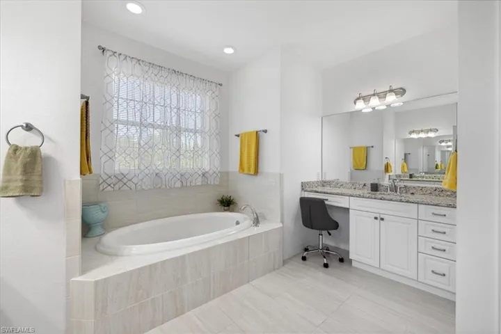 Full Master bathroom with vanity, a garden tub, and light tile patterned floors