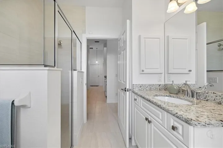BathroomGuest featuring vanity, a shower stall, and light tile patterned flooring