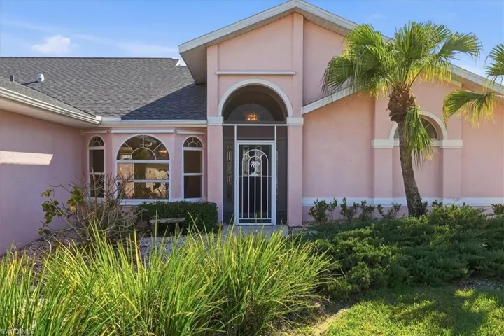 Entrance to property featuring stucco finish over block construction and a shingled roof