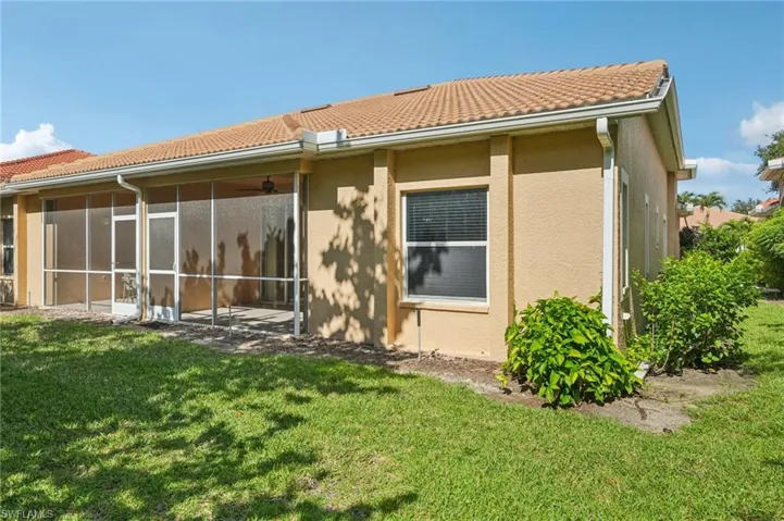 Back of property with a tiled roof, stucco siding, a lawn, and a sunroom