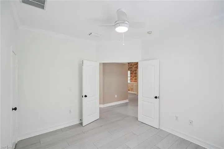 Spare room with ceiling fan, ornamental molding, and light wood-style floors