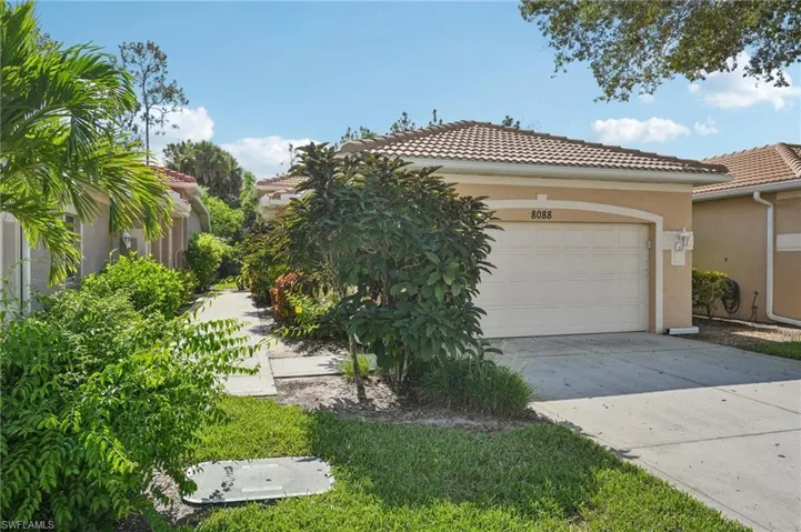View of front of house featuring a tile roof, stucco siding, driveway, and a garage