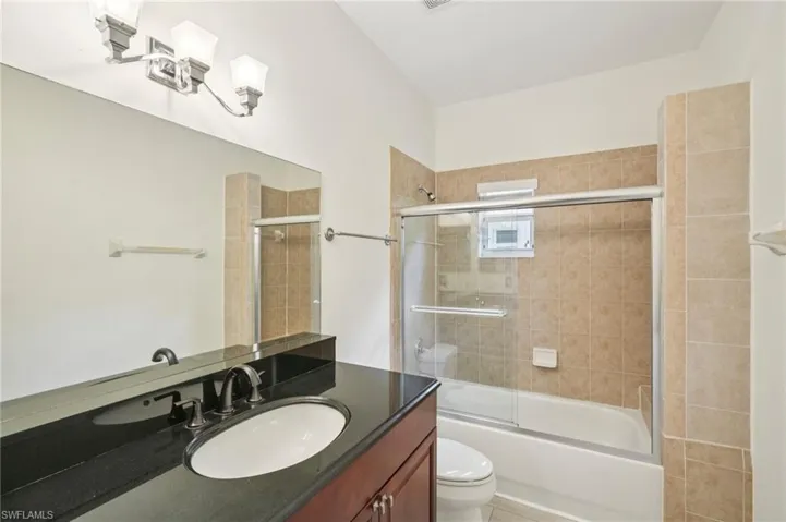 Full bath featuring vanity, enclosed tub / shower combo, and tile patterned flooring