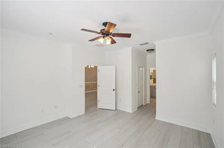 Unfurnished bedroom with crown molding, light wood-type flooring, and a ceiling fan