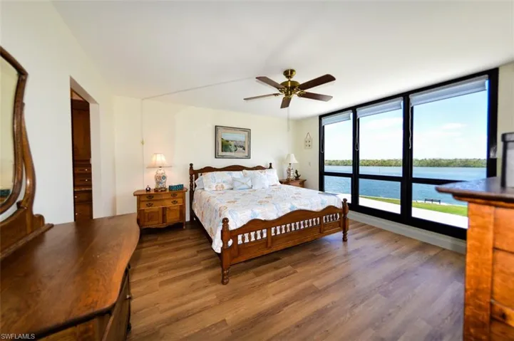 OWNER'S SUITE WITH DIRECT ESTERO BAY VIEWS.  LUXURY VINYL TILE WOOD LOOK PLANK FLOORING.  ZEBRA BLINDS.  ENTRANCE TO EN-SUITE BATH AND WALK-IN CLOSET IS TO LEFT.