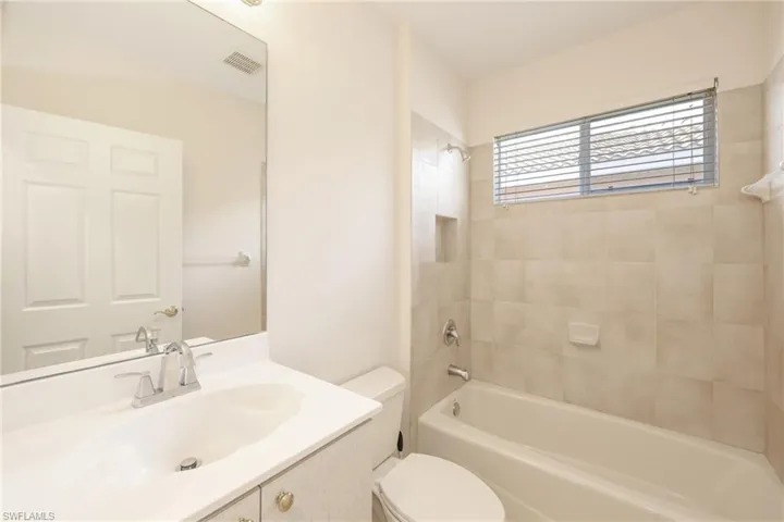 Full bathroom with toilet, tiled shower / bath combo, and vanity