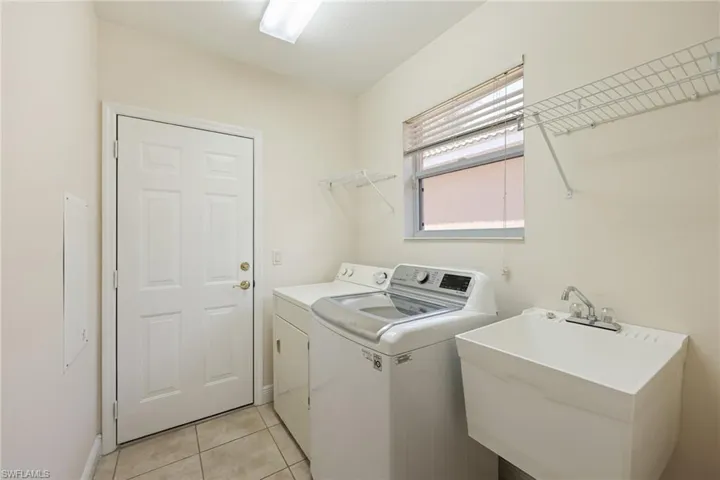 Clothes washing area featuring sink, separate washer and dryer, and light tile patterned floors