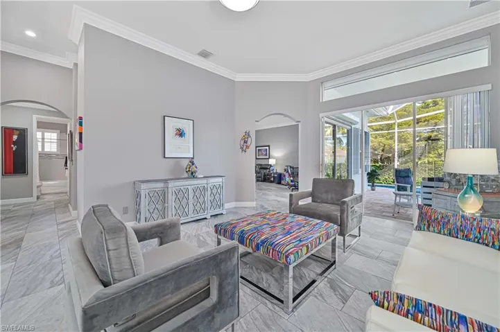 Spacious living area featuring updated tile, crown molding, sliding glass doors to covered lanai !