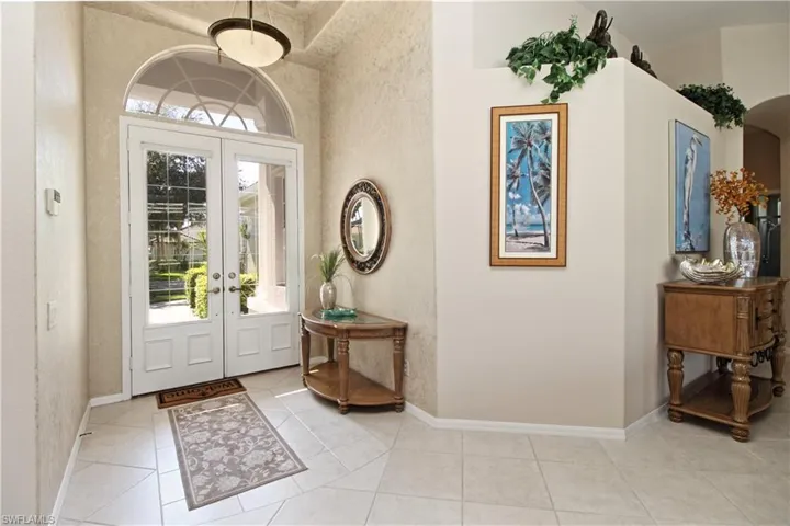 Entryway with light tile patterned floors, french doors, and arched walkways