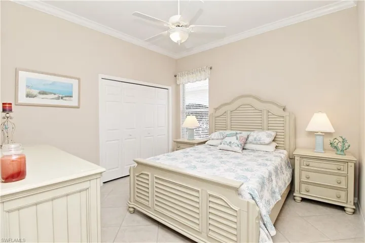 Bedroom with ornamental molding, a closet, ceiling fan, and light tile patterned floors
