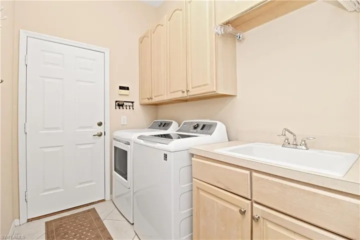 Laundry room with cabinet space, washing machine and dryer, and light tile patterned floors