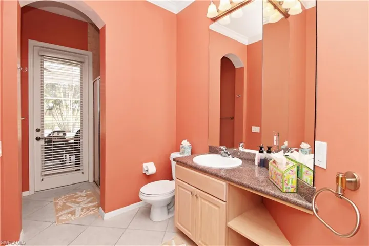 Full bathroom with a stall shower, vanity, light tile patterned floors, and crown molding