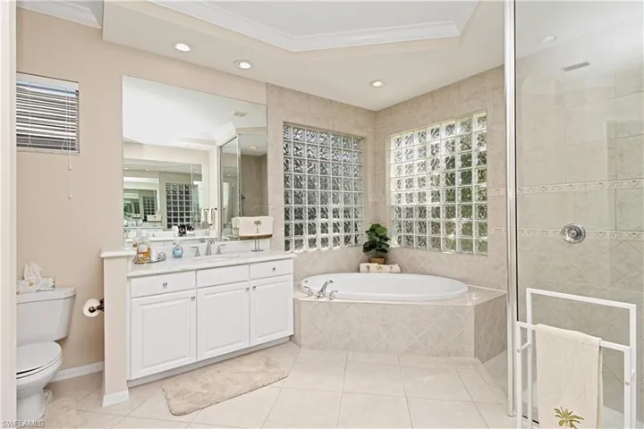 Full bathroom with ornamental molding, a stall shower, a garden tub, vanity, and light tile patterned floors