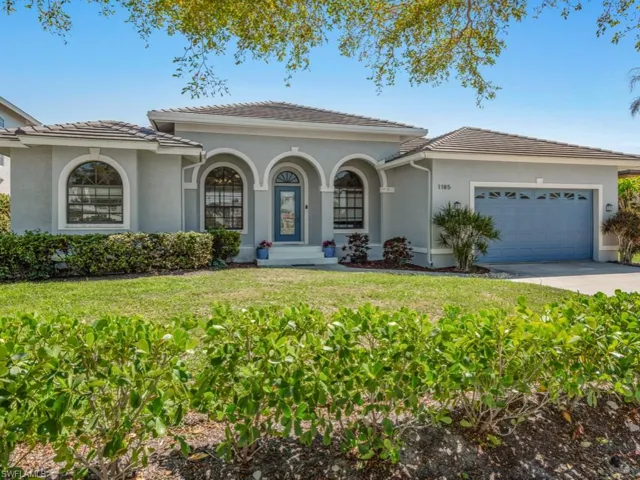 Mediterranean / spanish-style home with a tile roof, stucco siding, an attached garage, driveway, and a front lawn