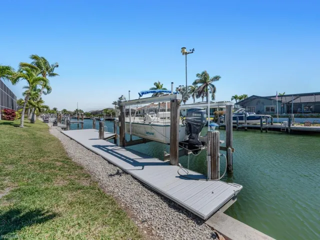 View of dock featuring boat lift, a water view, and a yard