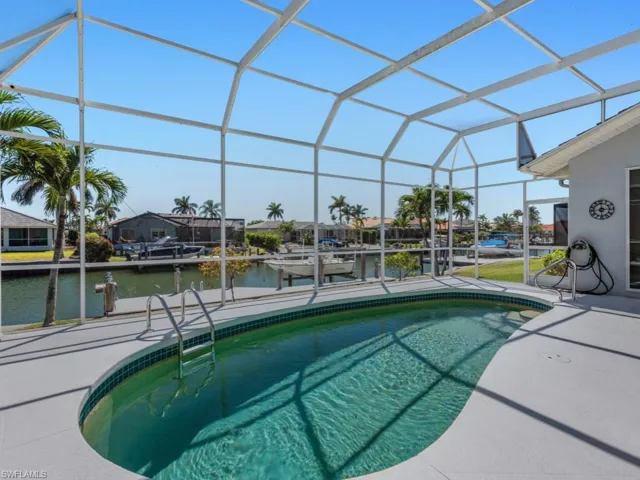 Outdoor pool with a lanai, a water view, a patio, and a boat dock