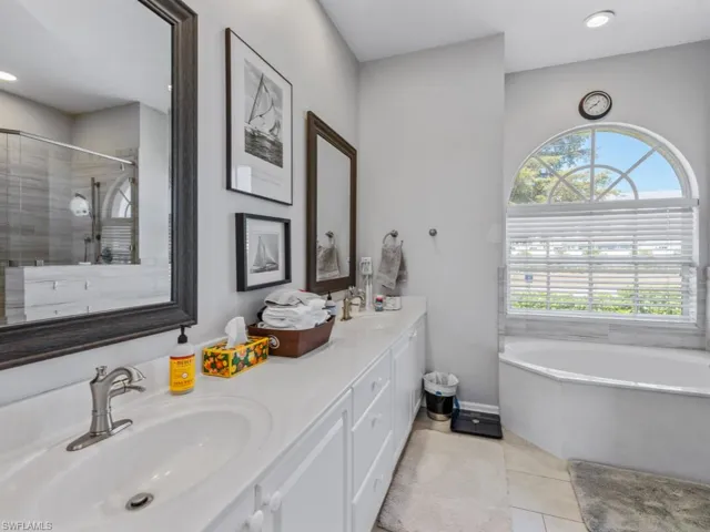 Bathroom featuring tile patterned flooring, a sink, a washtub, and a shower stall