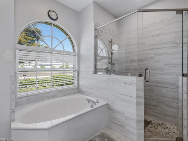 Bathroom with a stall shower, a bath, and a healthy amount of sunlight