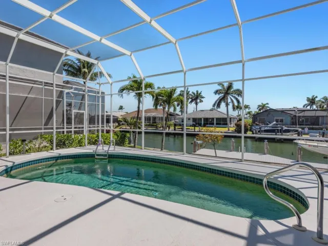 Pool featuring a water view, glass enclosure, and a patio area
