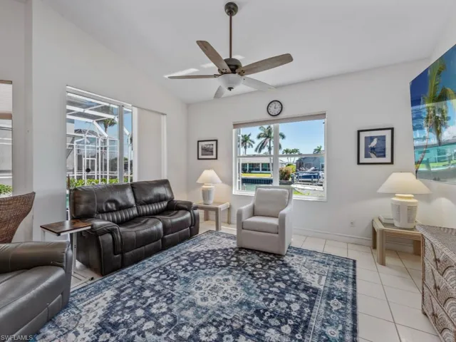 Living room featuring light tile patterned flooring, vaulted ceiling, ceiling fan, and a wealth of natural light