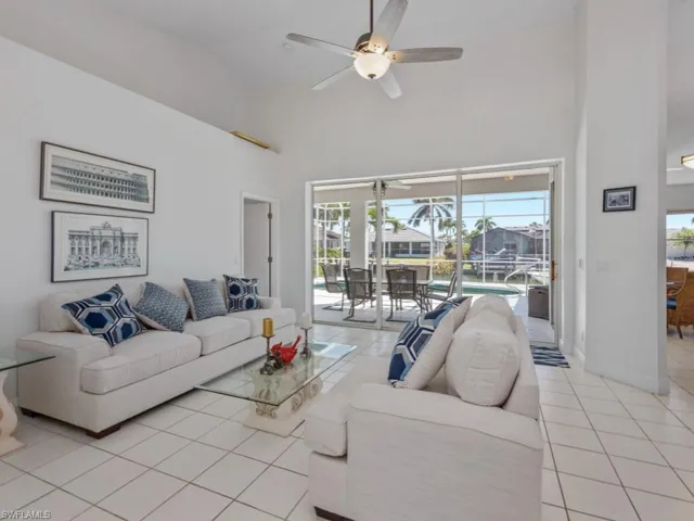 Living area featuring baseboards, a ceiling fan, high vaulted ceiling, and light tile patterned floors
