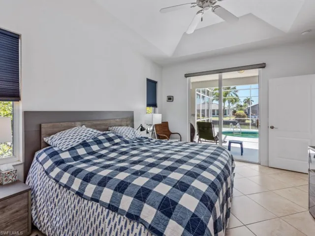 Bedroom featuring a tray ceiling, access to exterior, ceiling fan, and light tile patterned floors