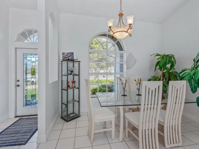 Dining space with light tile patterned floors, baseboards, and a notable chandelier
