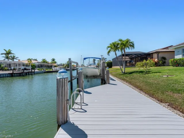 View of dock with a lawn, a lanai, a water view, and a residential view