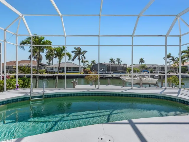Pool with glass enclosure, a residential view, a water view, and a patio area