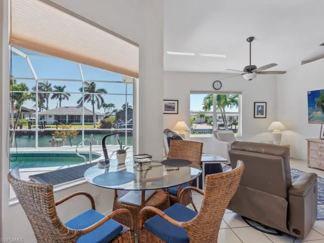 Dining area featuring light tile patterned flooring, a sunroom, a water view, and ceiling fan